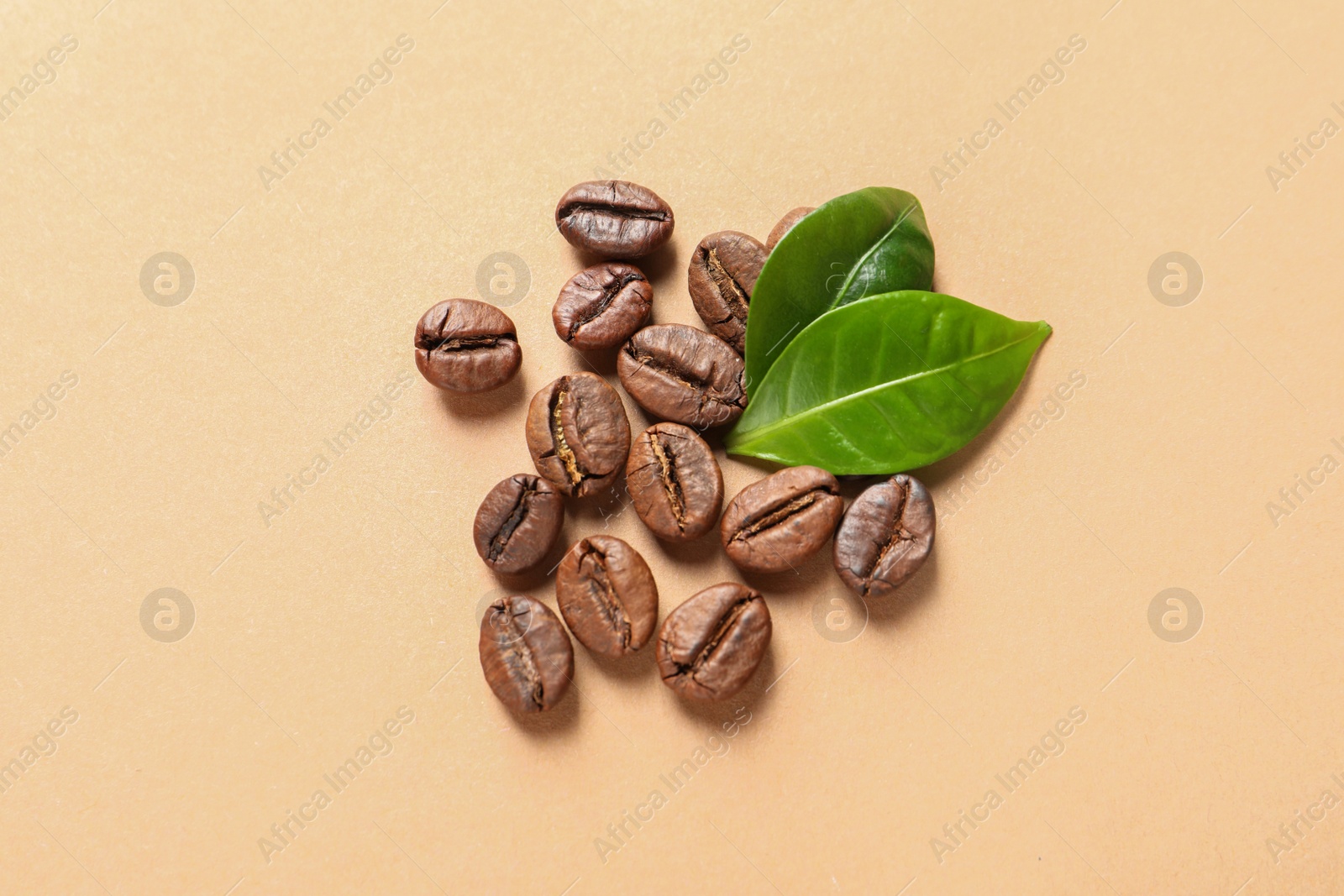 Photo of Fresh green coffee leaves and beans on light orange background, flat lay
