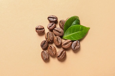 Fresh green coffee leaves and beans on light orange background, flat lay