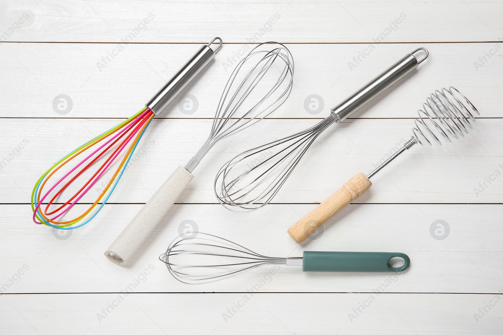 Photo of Different whisks on white wooden table, flat lay