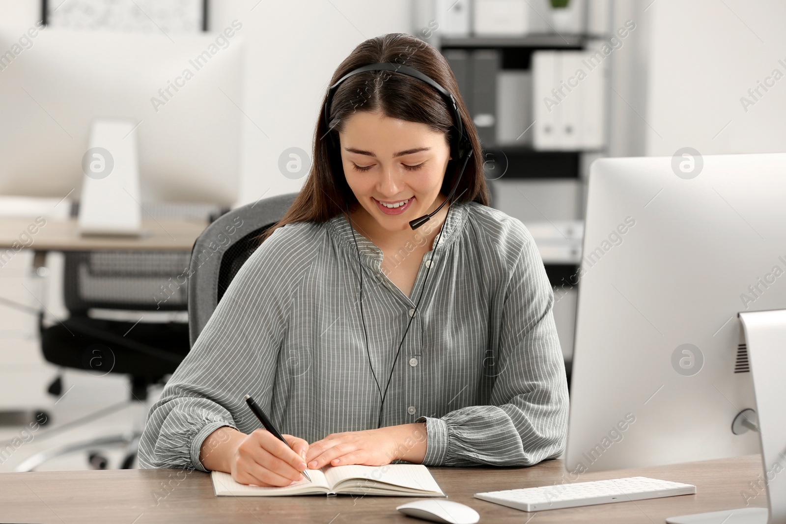 Photo of Hotline operator with headset working on computer in office