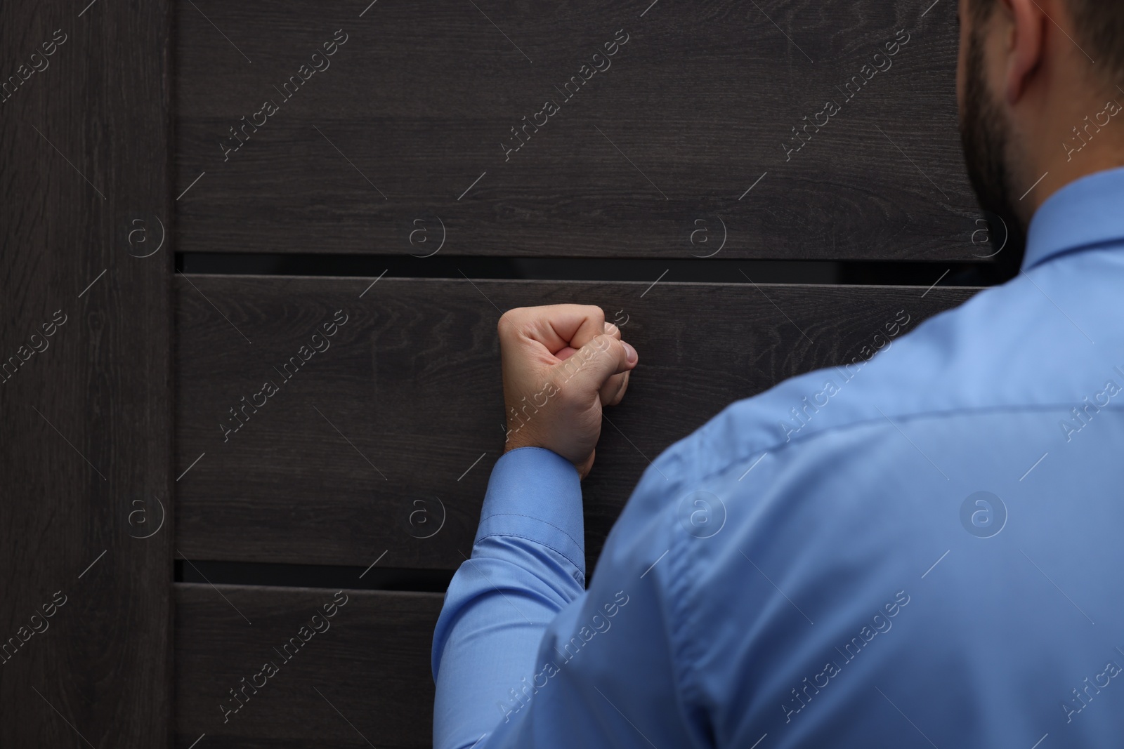 Photo of Collection agent knocking on wooden door, closeup