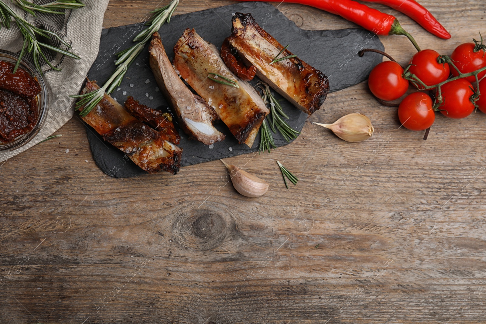 Photo of Tasty grilled ribs with rosemary on wooden table, flat lay. Space for text