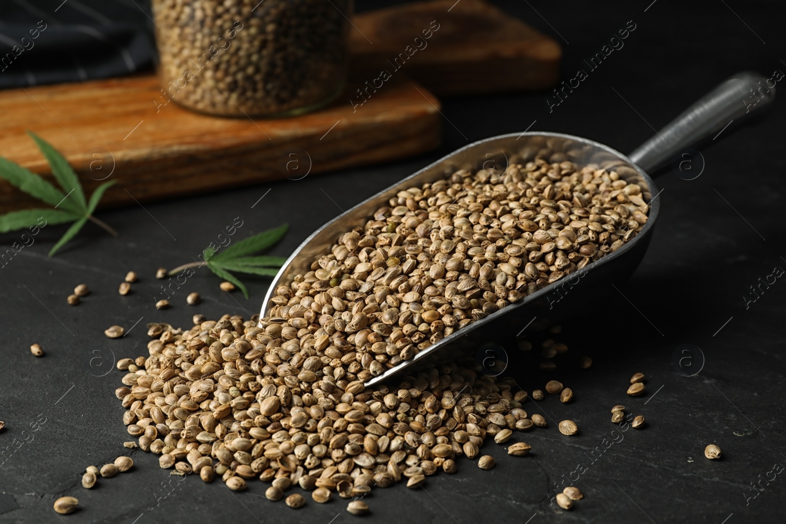 Photo of Raw organic hemp seeds in scoop on black table