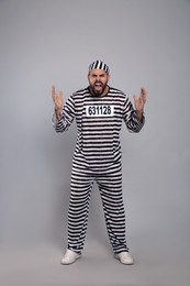 Photo of Emotional prisoner in special uniform on grey background