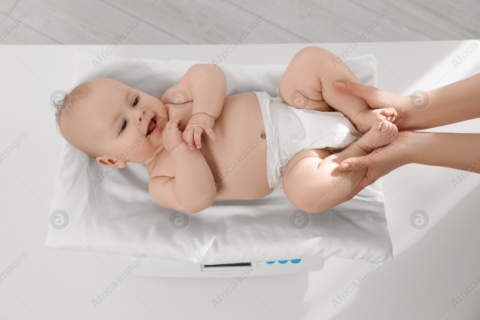 Photo of Pediatrician weighting cute little baby in clinic, closeup