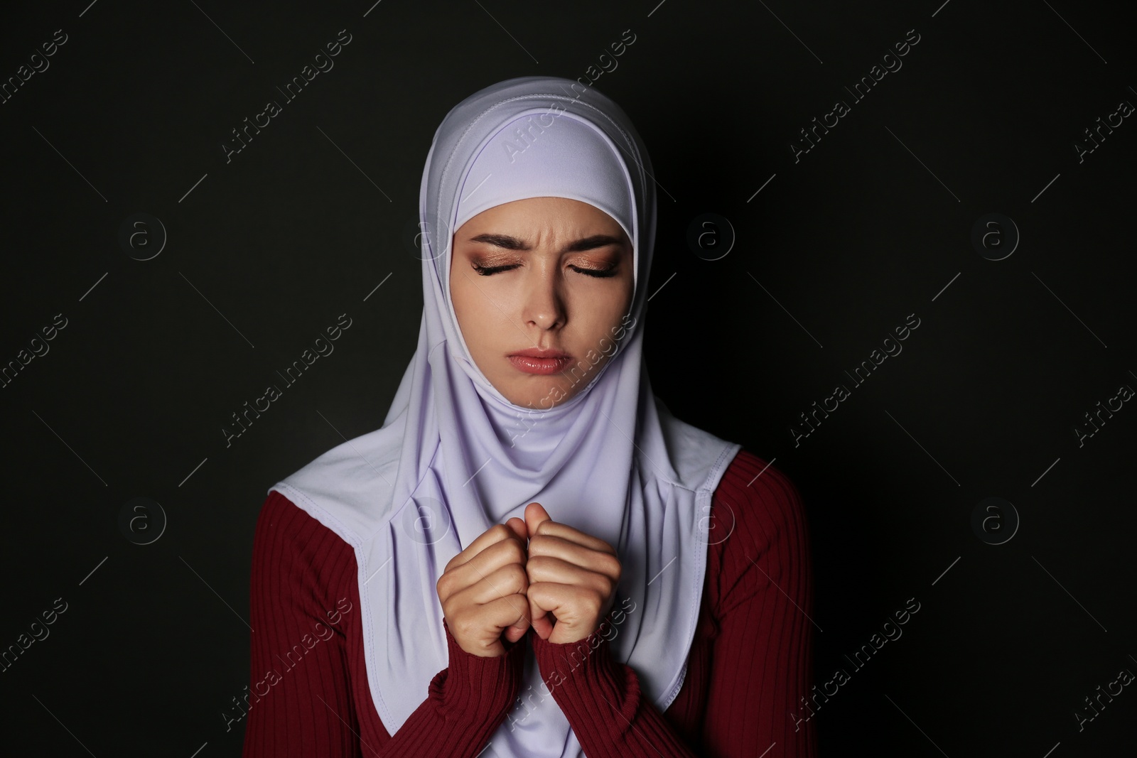 Photo of Portrait of Muslim woman in hijab  praying on dark background