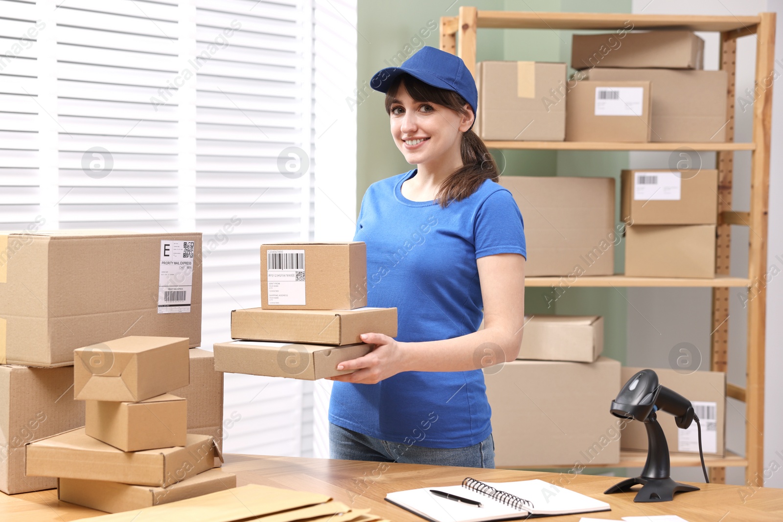 Photo of Parcel packing. Post office worker with parcels at wooden table indoors