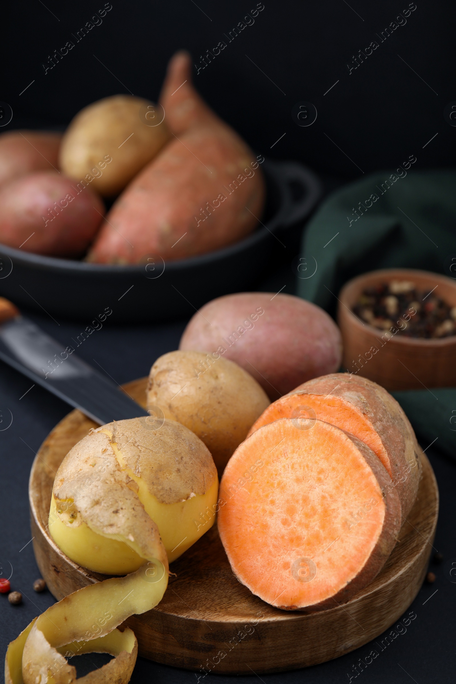 Photo of Wooden board with fresh potatoes on black table