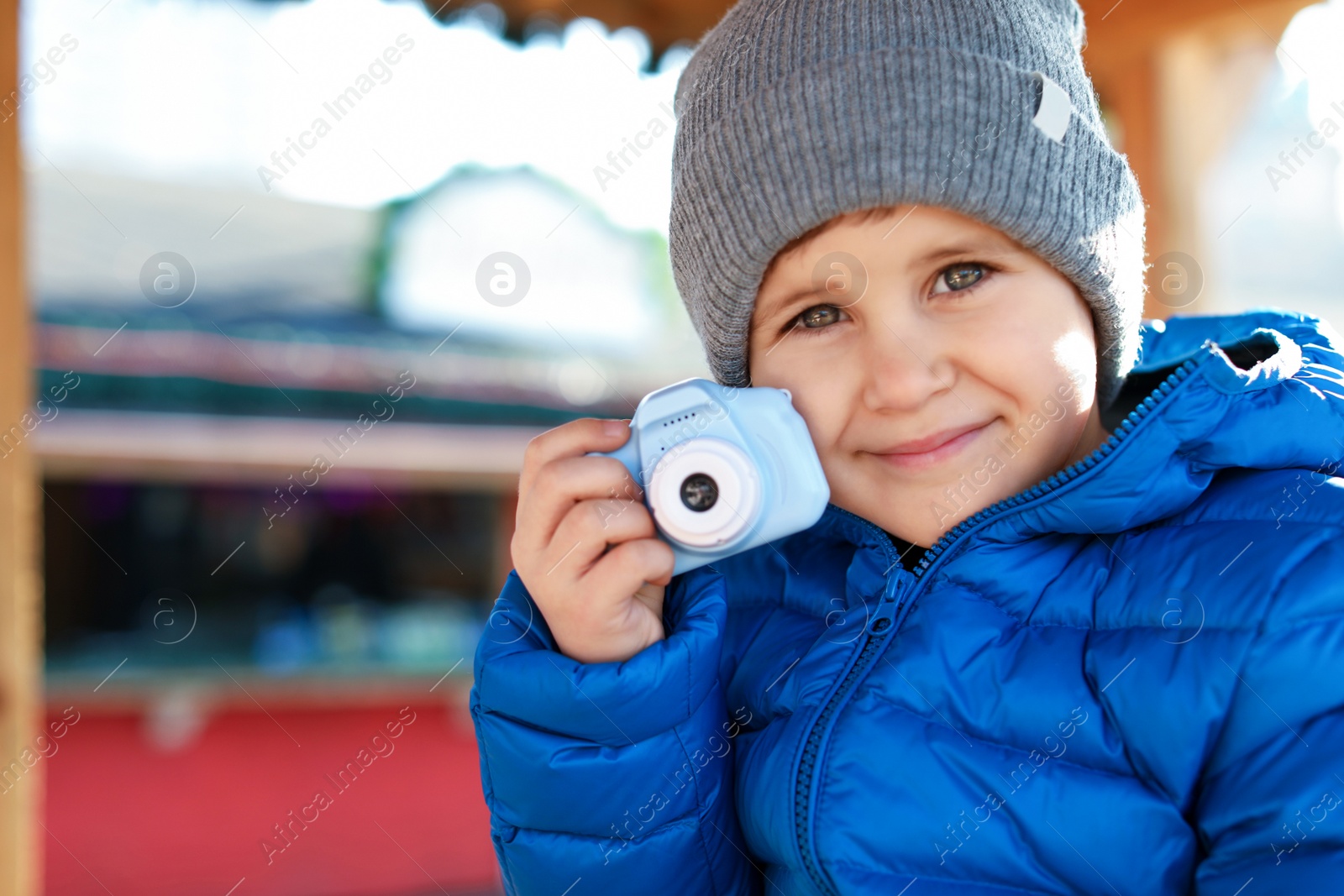 Photo of Cute little photographer with toy camera outdoors