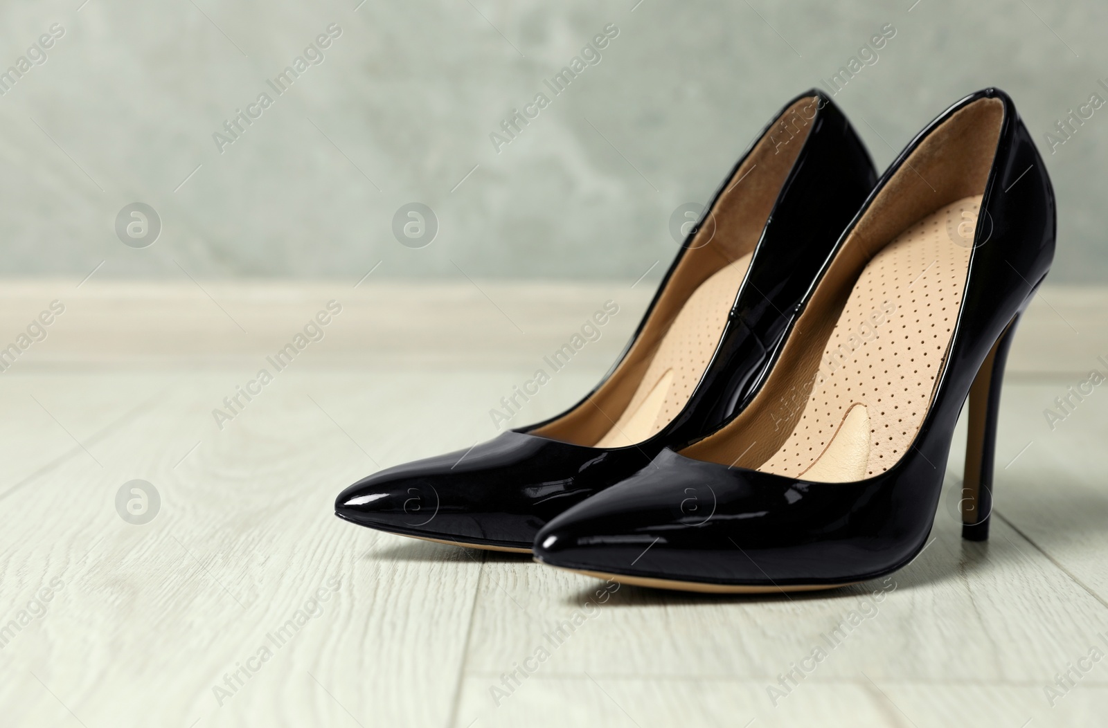 Photo of Orthopedic insoles in high heel shoes on floor, closeup. Space for text