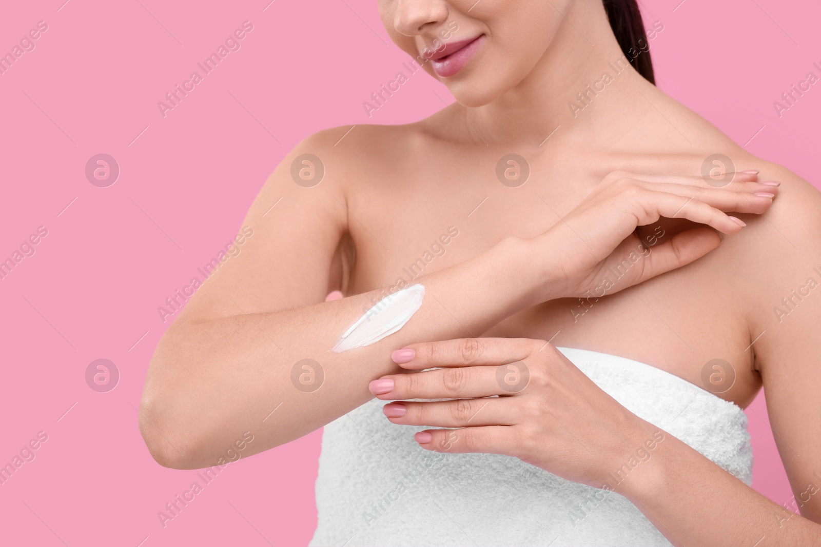 Photo of Woman with smear of body cream on her arm against pink background, closeup