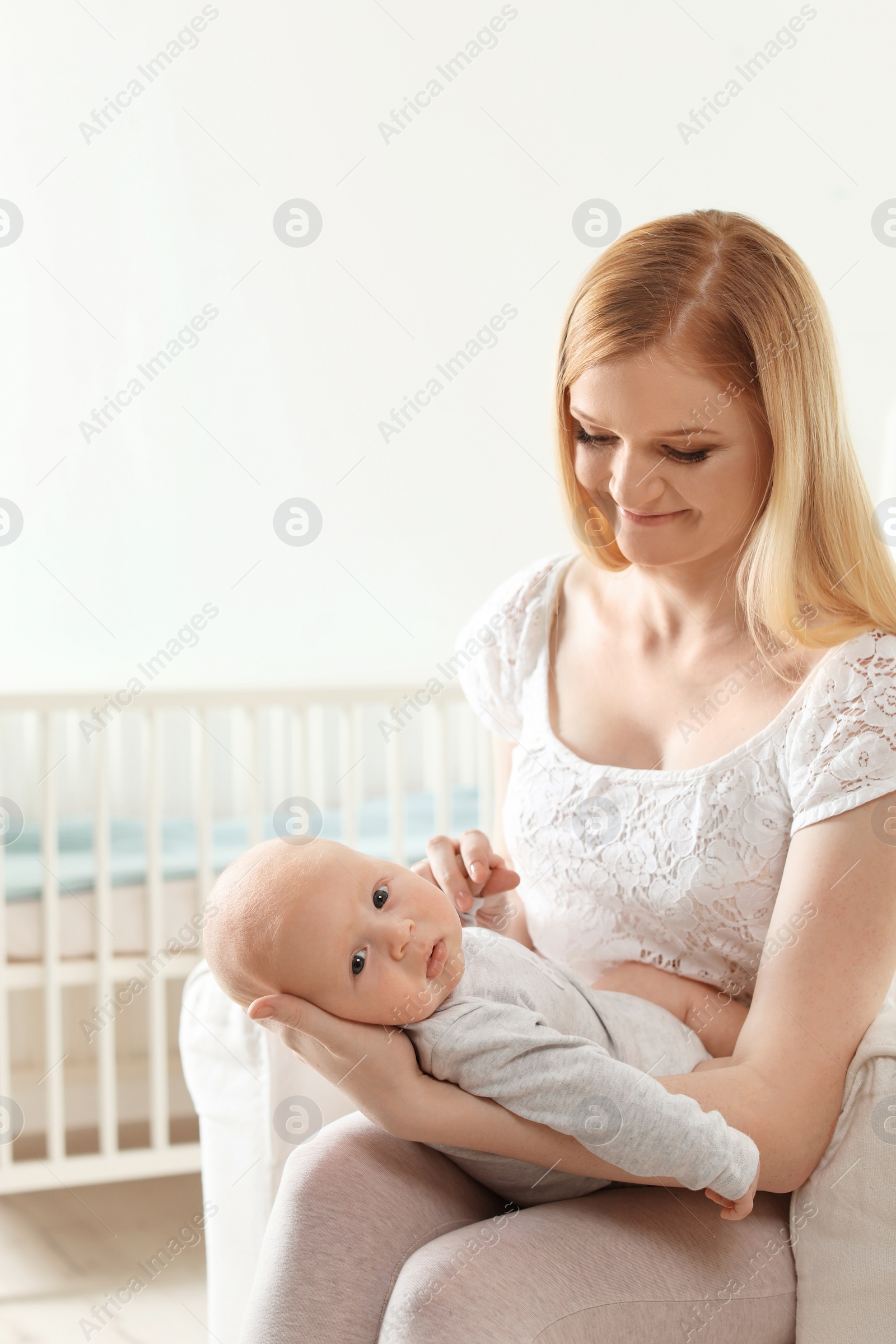 Photo of Happy mother with her baby sitting in armchair at home