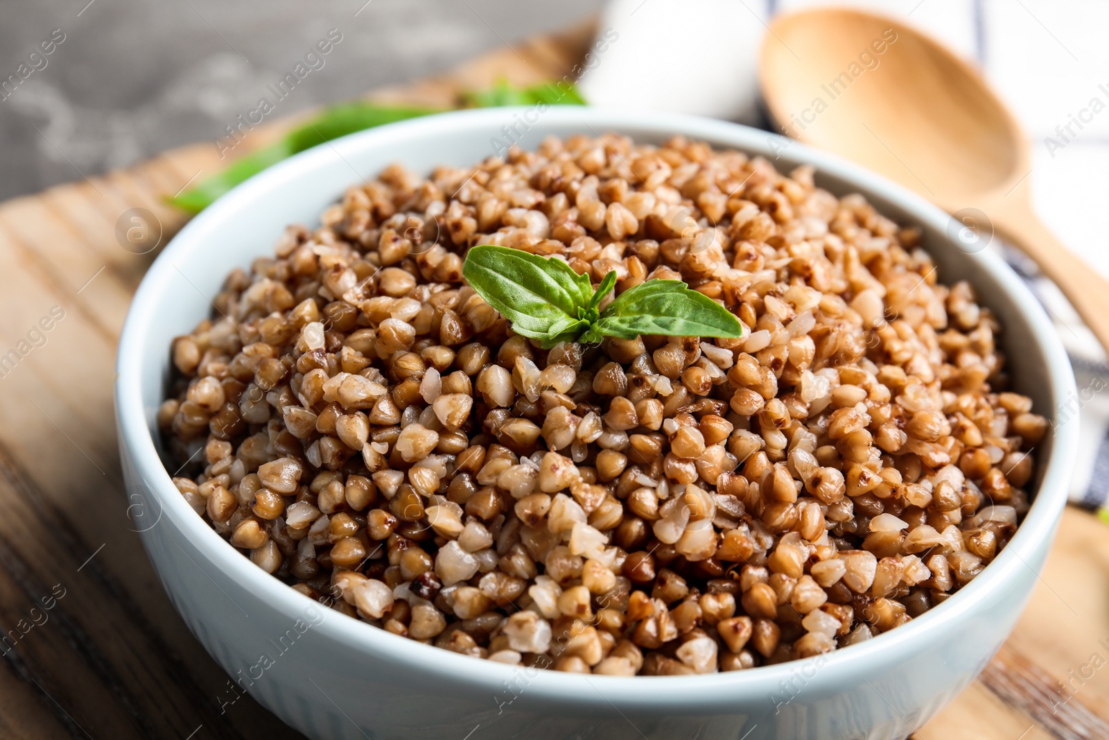 Photo of Bowl of buckwheat porridge with basil on table, closeup