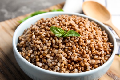 Bowl of buckwheat porridge with basil on table, closeup