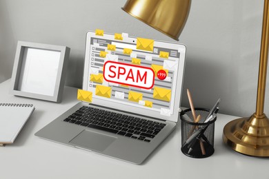 Image of Spam warning message in email software. Envelope illustrations popping out of laptop display on office desk