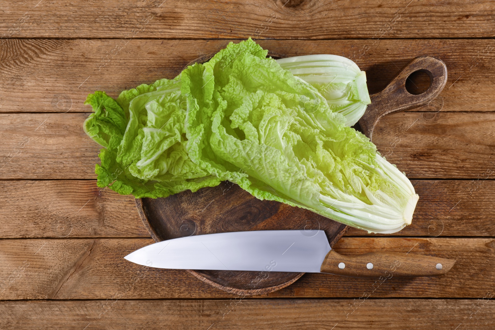 Photo of Halves of fresh ripe Chinese cabbage and knife on wooden table, flat lay
