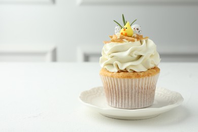 Photo of Tasty Easter cupcake with vanilla cream on white table, space for text