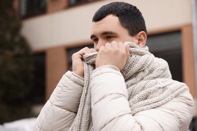 Sick young man coughing on city street. Cold symptoms