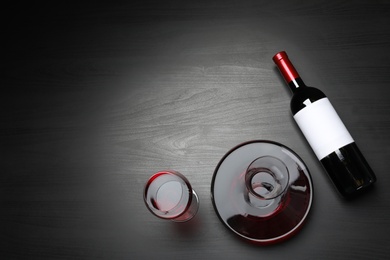 Photo of Decanter, glass and bottle with red wine on dark background, flat lay. Space for text