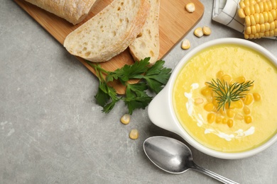 Photo of Delicious creamy corn soup served on grey table, flat lay