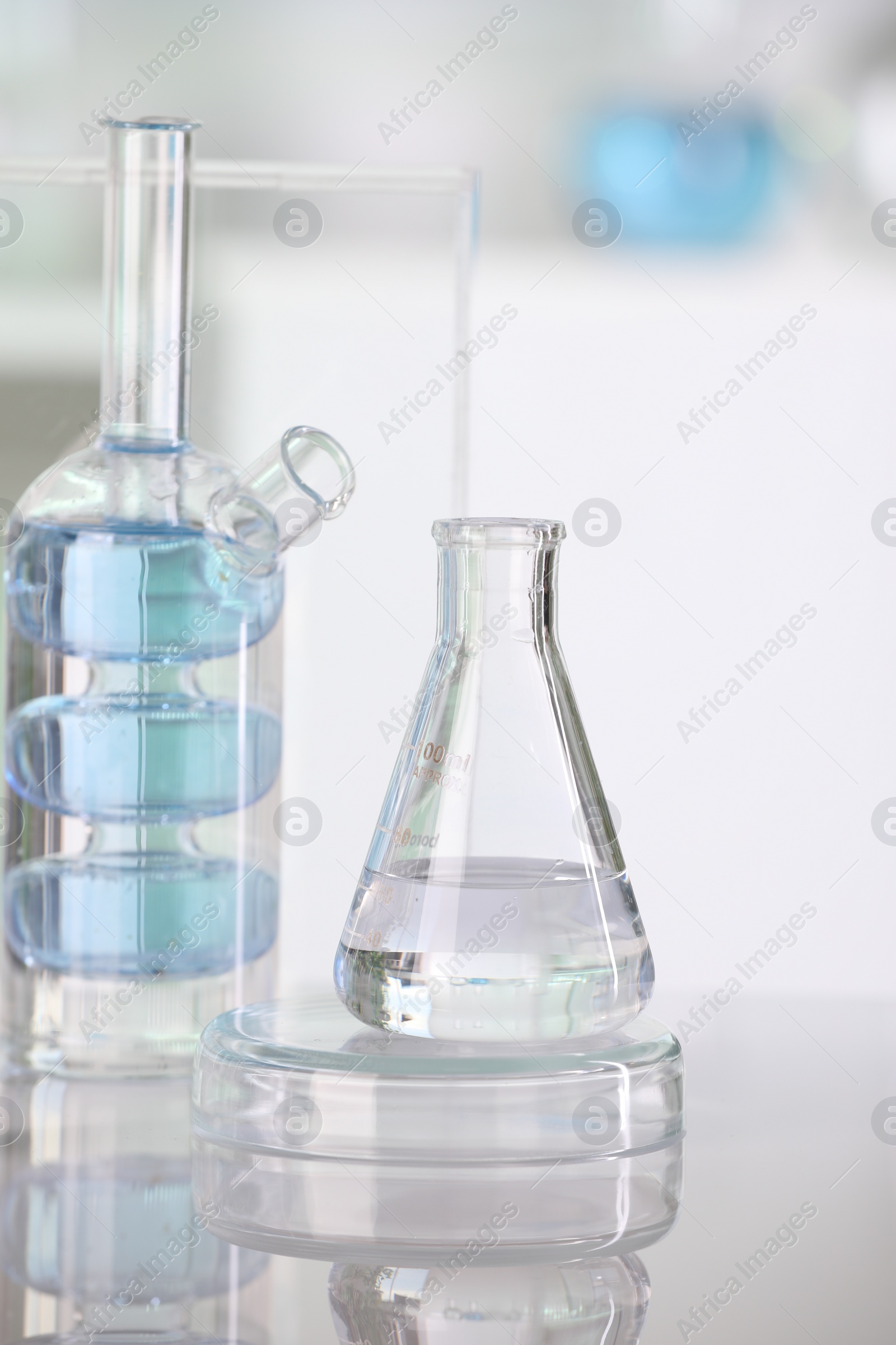 Photo of Laboratory analysis. Different glassware with liquid on white table against blurred background