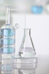 Photo of Laboratory analysis. Different glassware with liquid on white table against blurred background