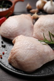 Photo of Raw chicken thighs with rosemary and spices on wooden table, closeup