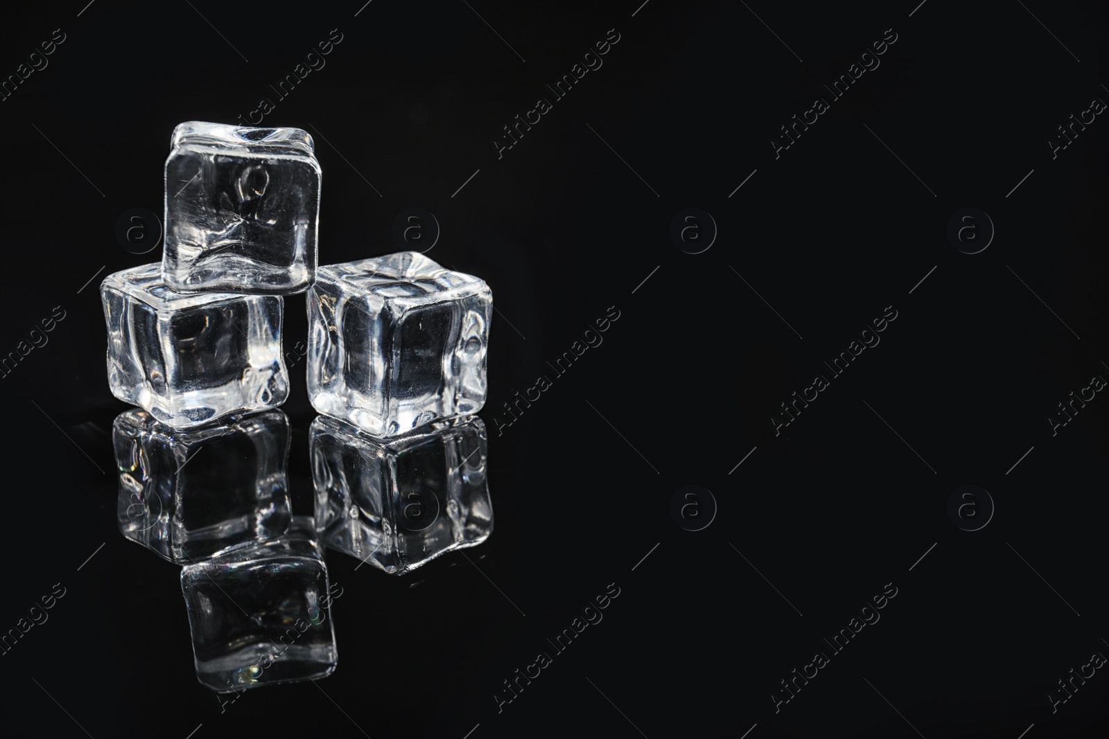 Photo of Pile of crystal clear ice cubes on black background. Space for text