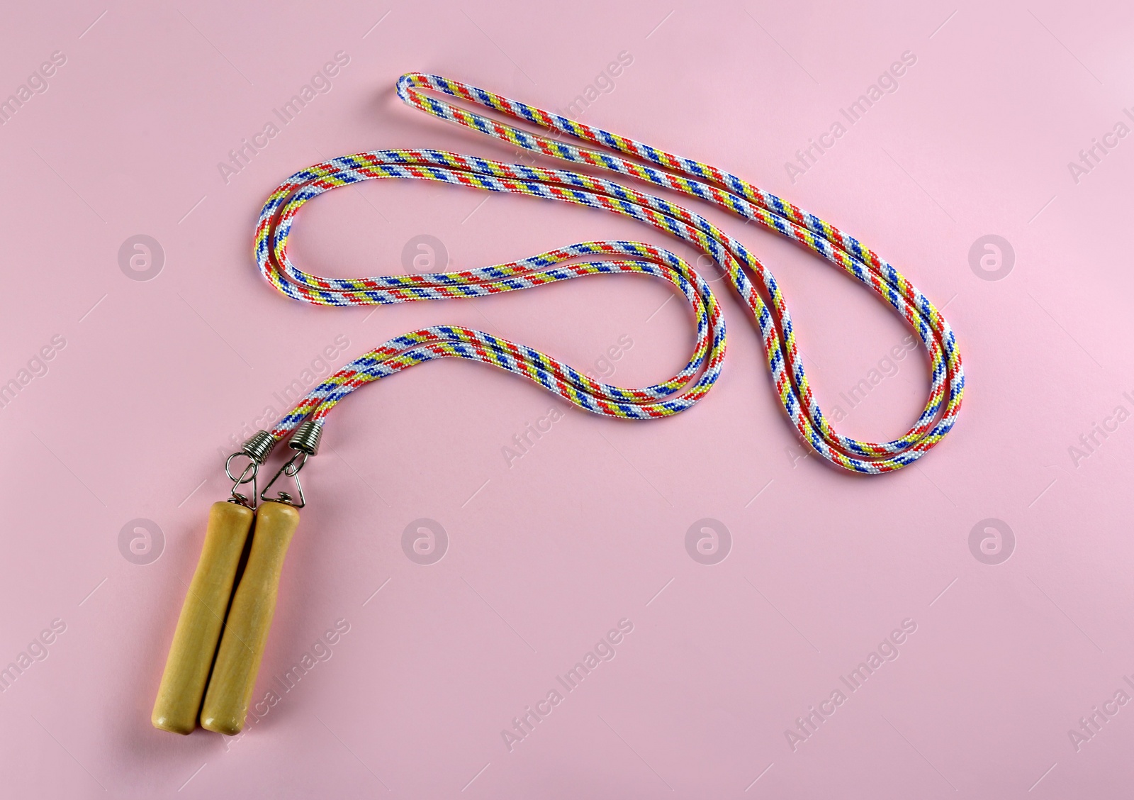 Photo of Skipping  rope on pink background, top view. Sports equipment