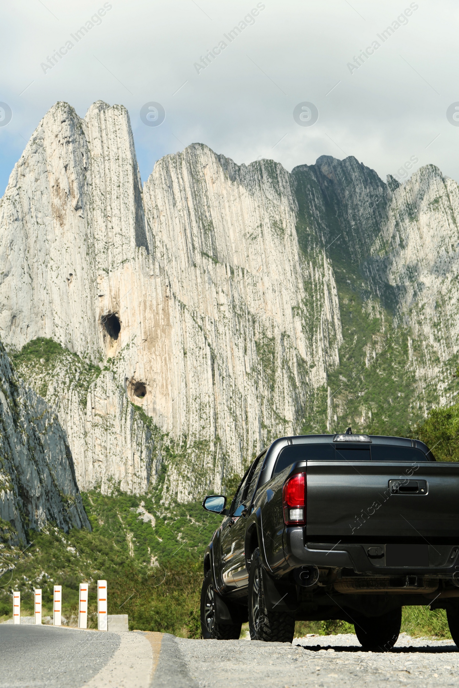 Photo of Picturesque view of big mountains and trees near road with car