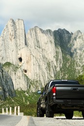 Photo of Picturesque view of big mountains and trees near road with car