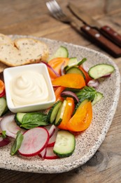 Plate of delicious vegetable salad with mayonnaise and croutons on wooden table, closeup
