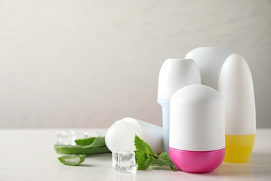 Roll-on deodorants, aloe and ice with mint on white wooden table, space for text