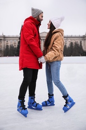 Image of Happy young couple skating at outdoor ice rink