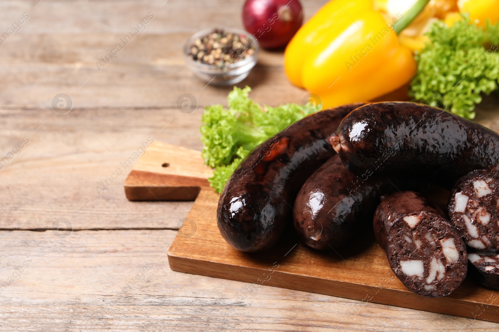 Photo of Tasty blood sausages served on wooden table, closeup. Space for text