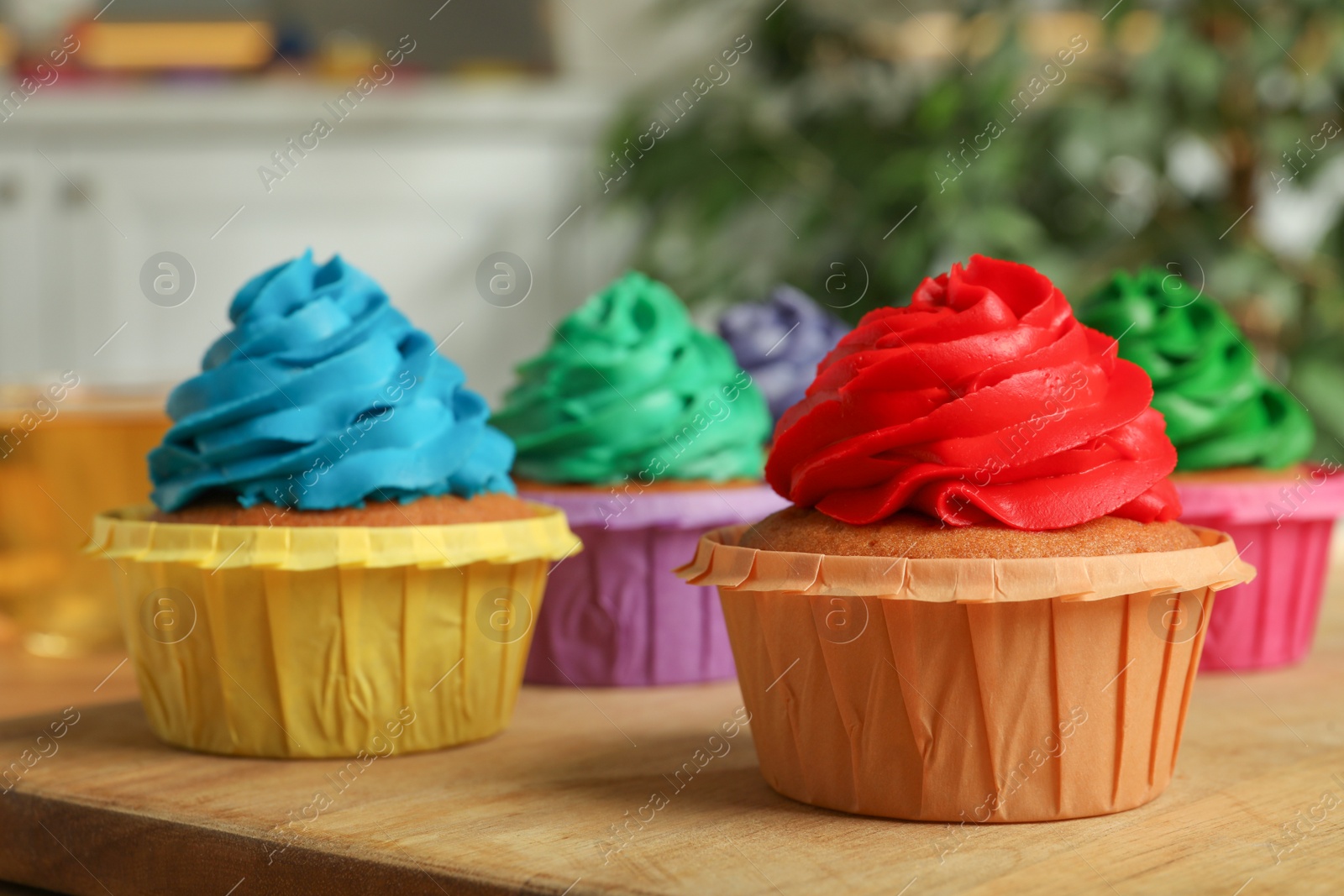 Photo of Delicious cupcakes with colorful cream on wooden table, closeup