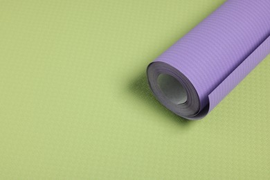 One violet wallpaper roll on green sample, space for text