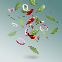Image of Bay leaves, onion rings, garlic cloves, dry red and black peppers falling on teal gradient background