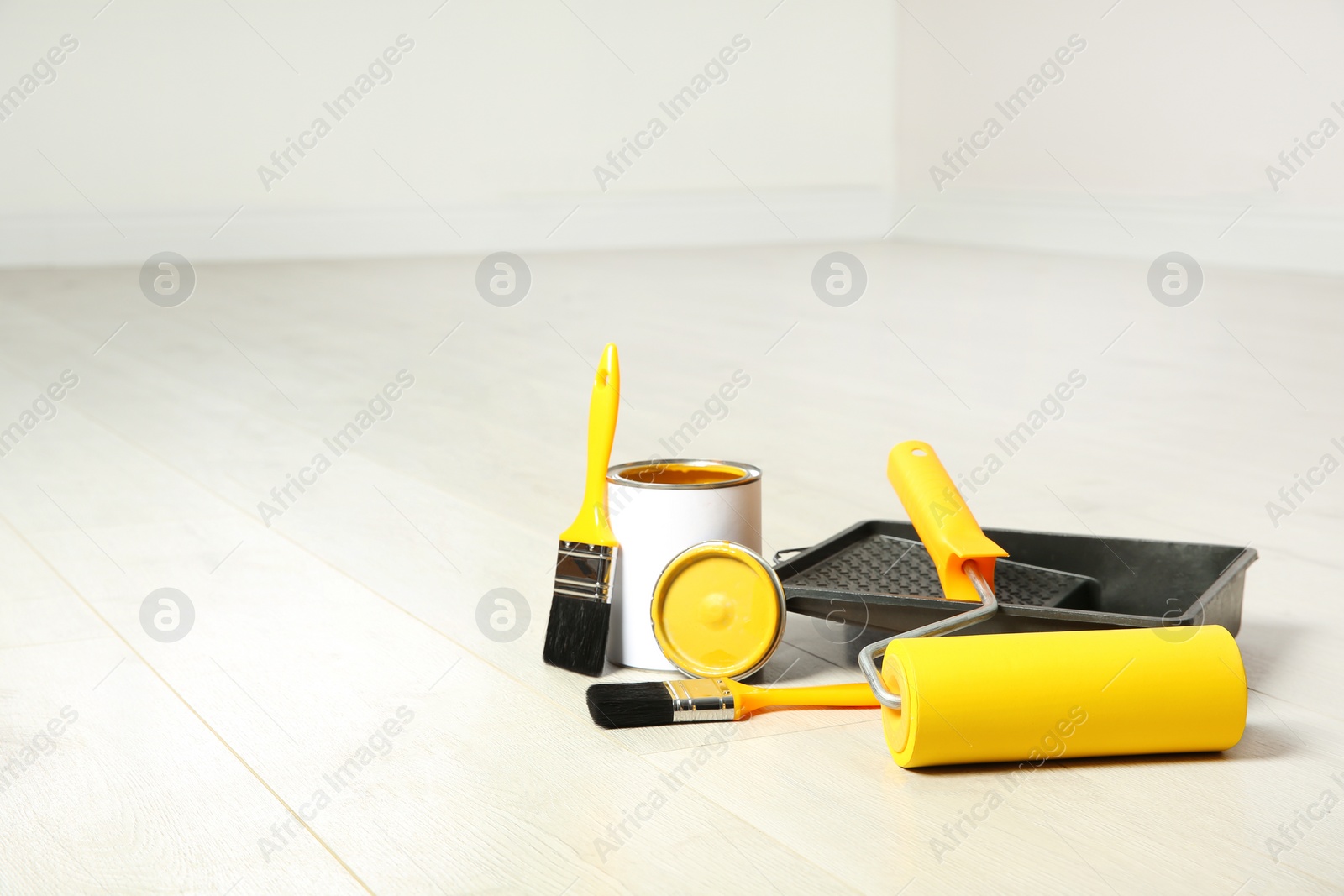 Photo of Can of paint and decorator tools on wooden floor indoors. Space for text