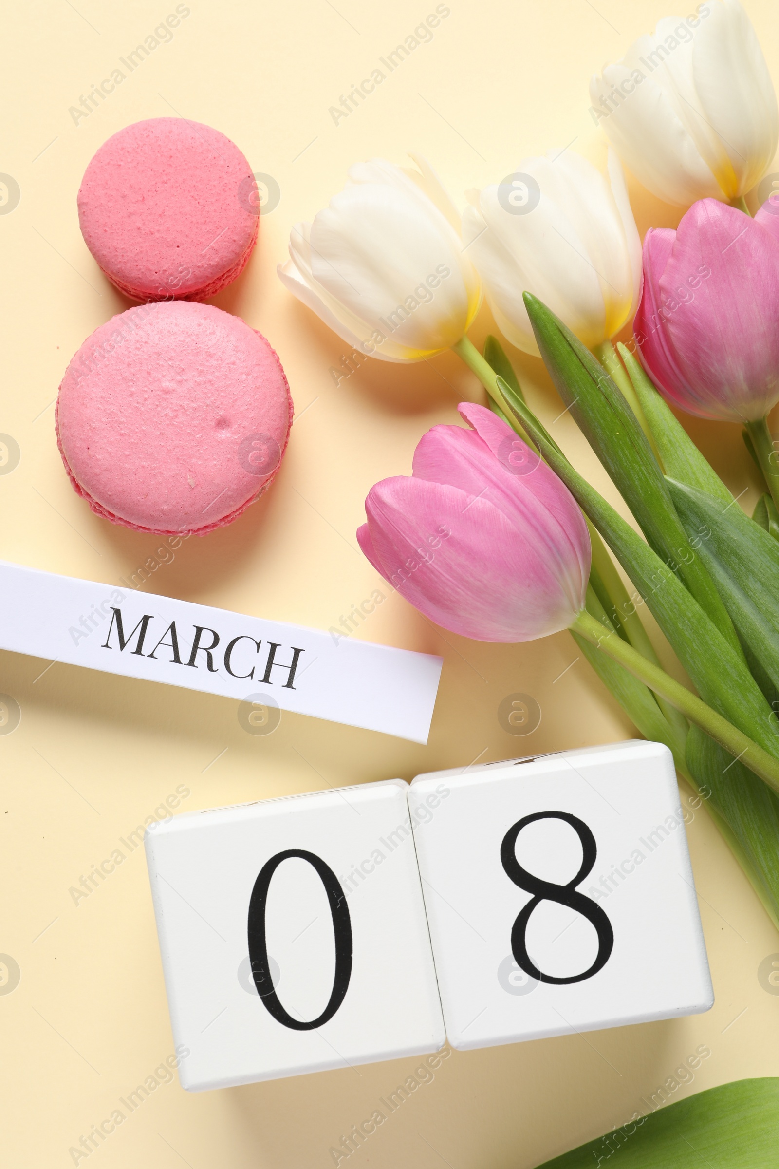 Photo of International Women's day - 8th of March. Macaron cookies, wooden block calendar and beautiful flowers on beige background, flat lay