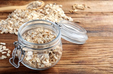 Photo of Glass jar with oatmeal on wooden table. Space for text