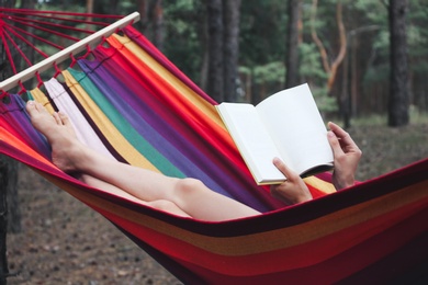 Photo of Woman with book relaxing in hammock outdoors on summer day, closeup