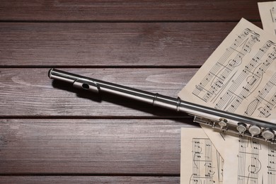 Sheets with musical notes and flute on wooden table. Space for text