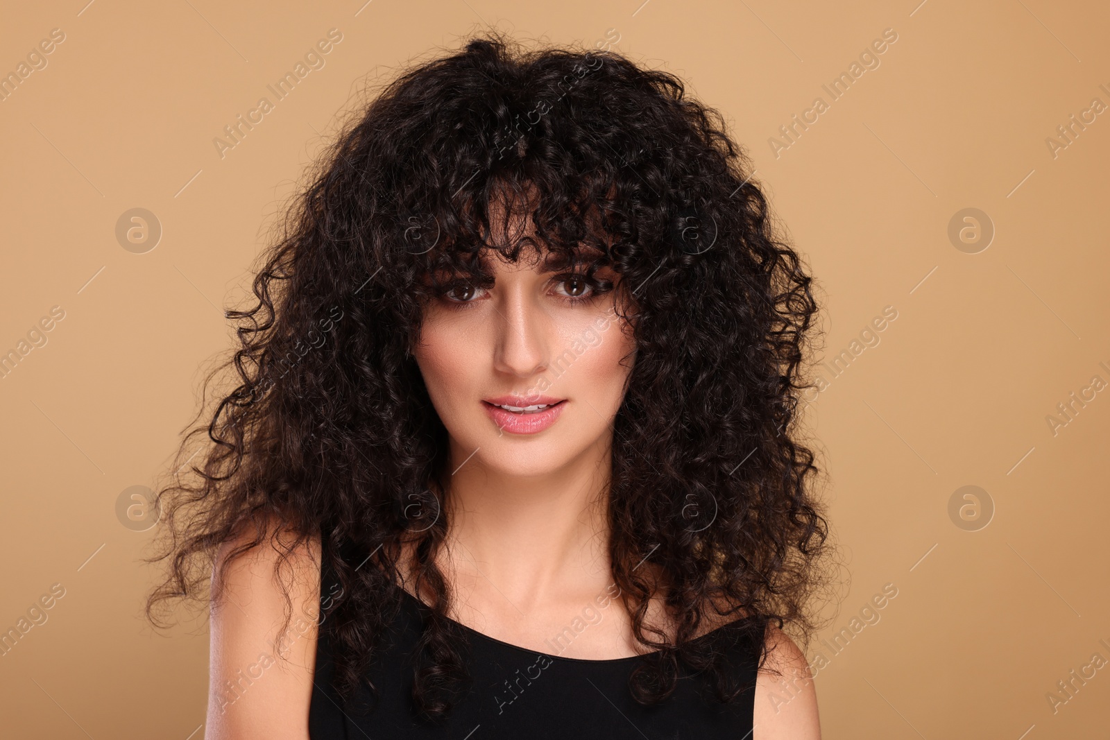 Photo of Beautiful young woman with long curly hair on beige background