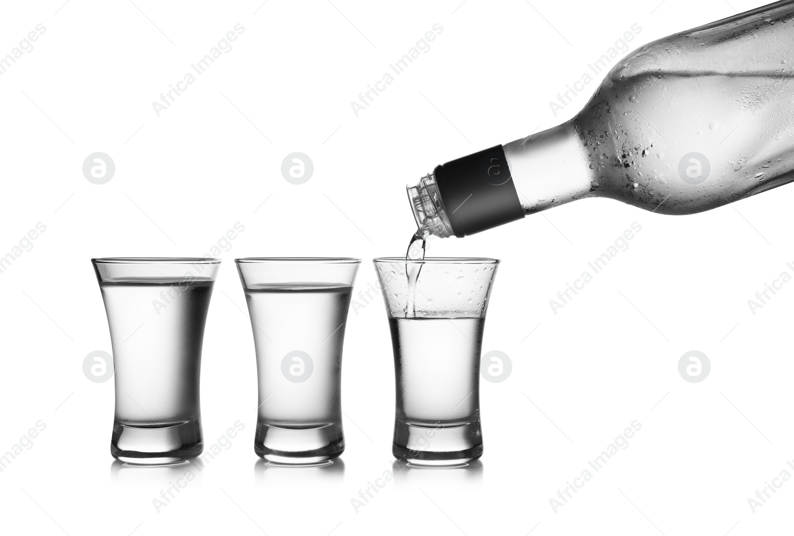 Photo of Pouring cold vodka into shot glass on white background