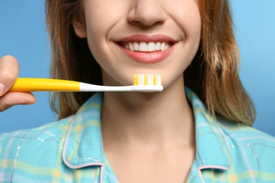 Photo of Young woman with toothbrush on color background, closeup