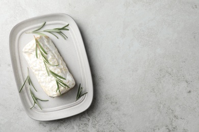 Photo of Delicious fresh goat cheese with rosemary on light grey table, top view. Space for text