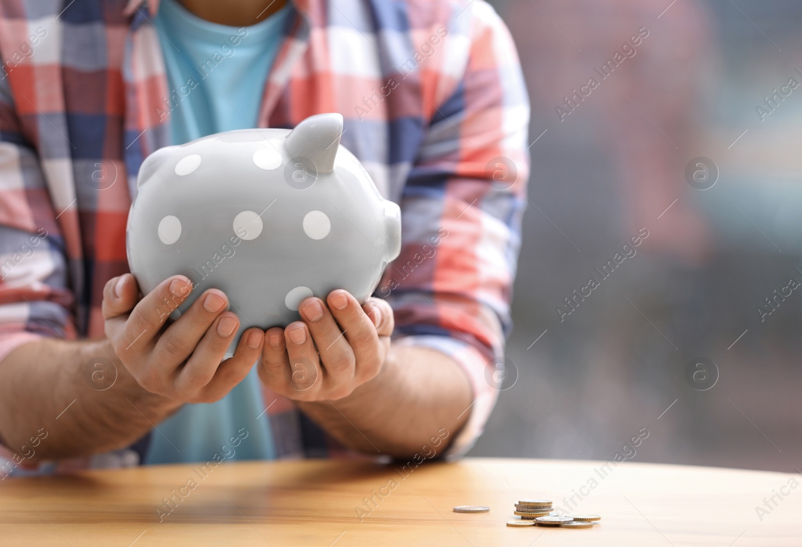 Photo of Man holding piggy bank at table, closeup. Space for text