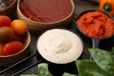 Different marinades and products on wooden table, closeup view