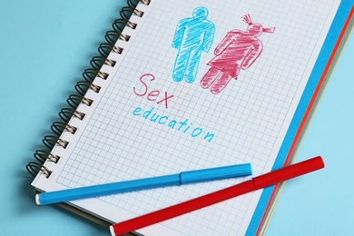 Photo of Notebook with phrase "SEX EDUCATION" on blue background, above view